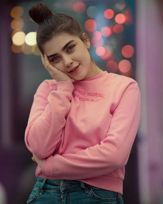 young woman standing by herself in a pink sweater