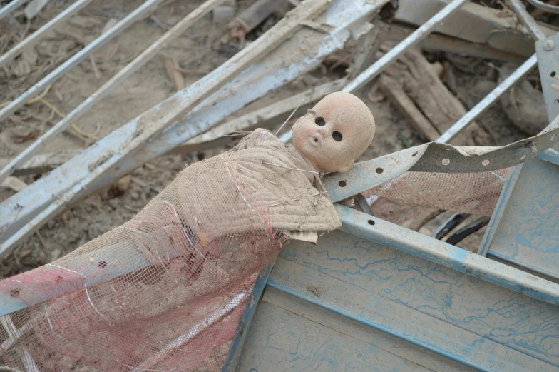 a doll is holding onto an old object outside