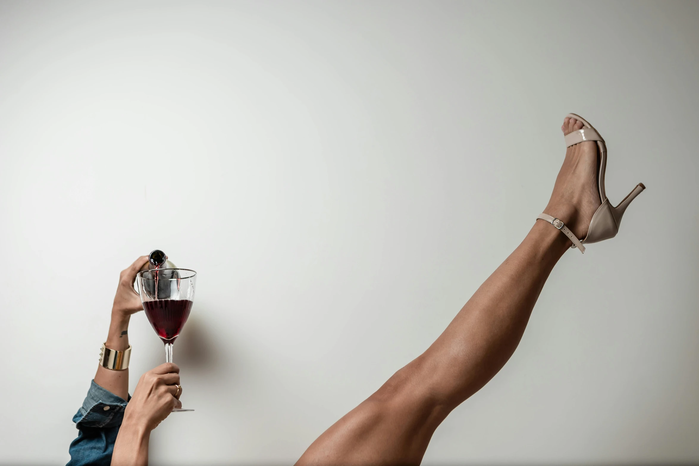 woman's feet and heels with a glass of wine