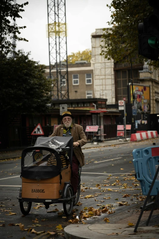 a man pulling a baby in a small cart down the street