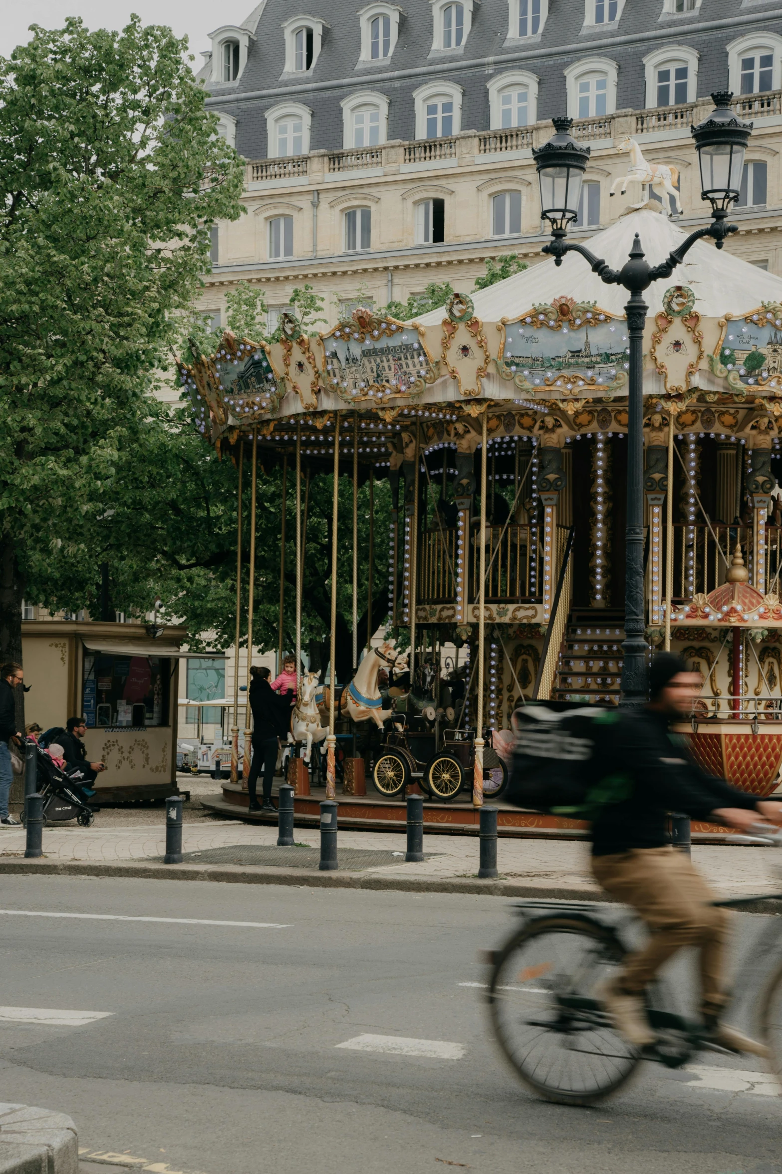 a person on a bike rides past a carousel