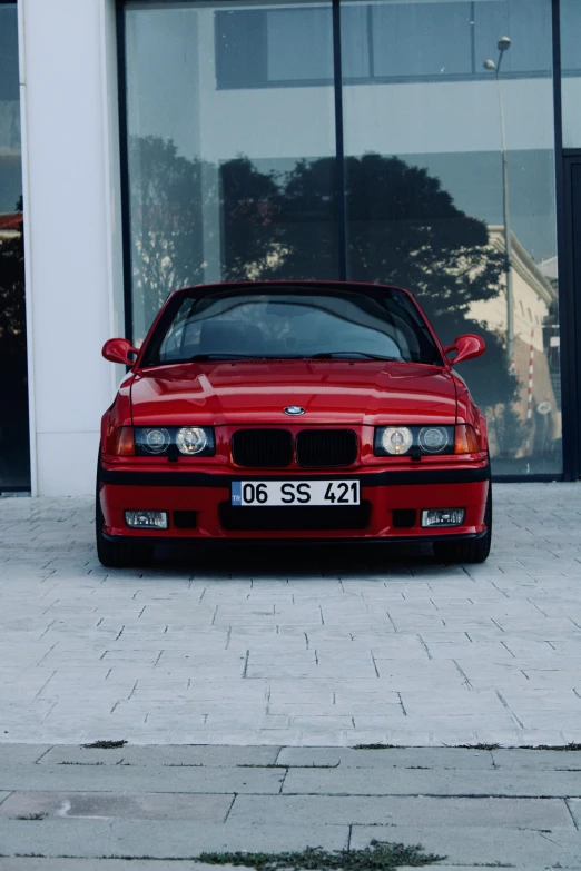 a red car sitting in front of an glass wall