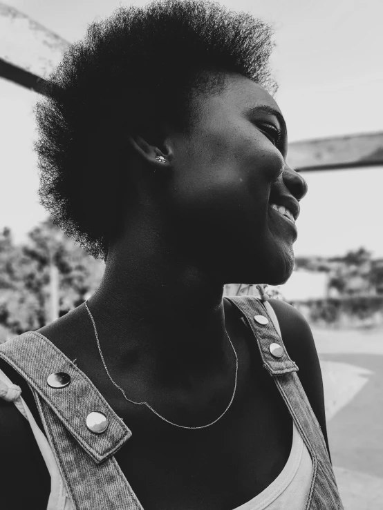 a woman in overalls smiling at the sky