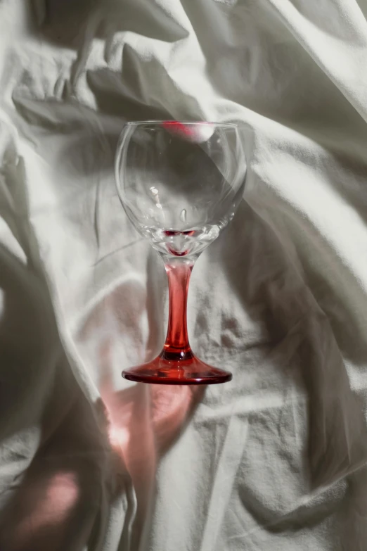 a pink wine glass laying on top of white sheets
