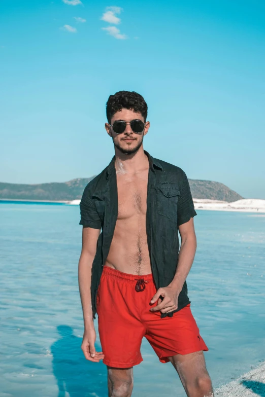 man with shirt and red shorts standing in water