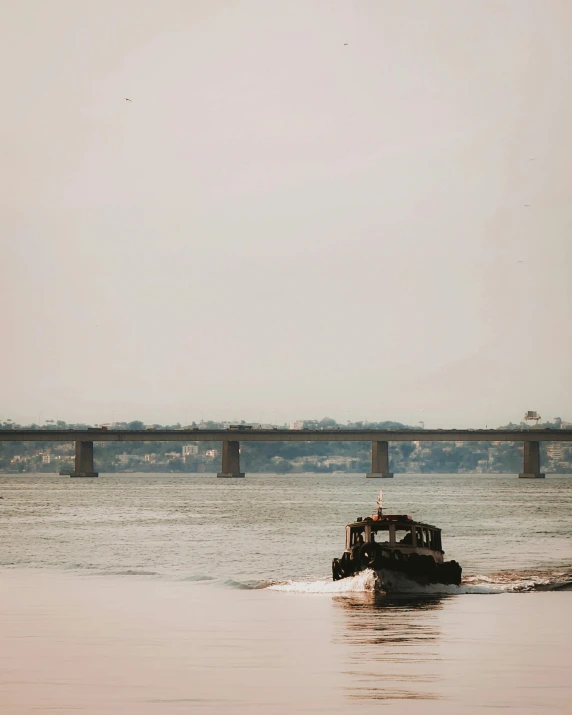 a boat sailing on a river with bridge over the water