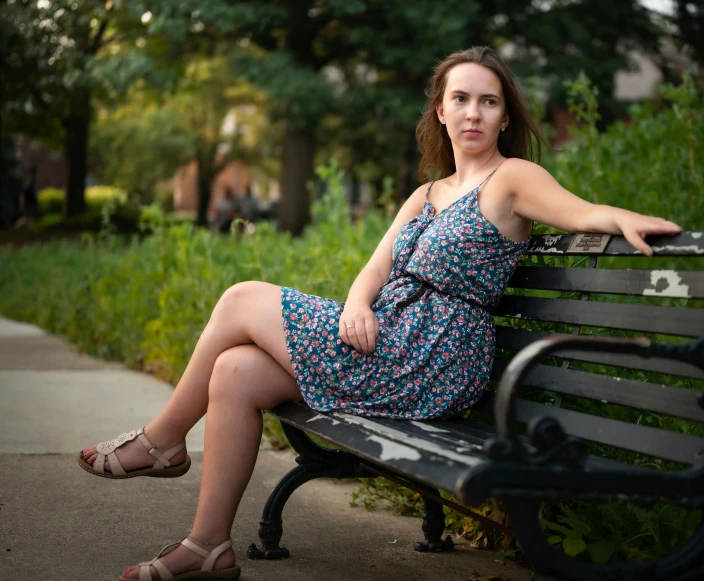 a woman sitting on a bench near grass