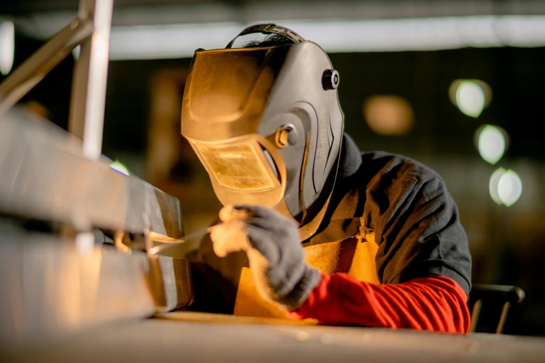 a person wearing a mask and welding on metal bars