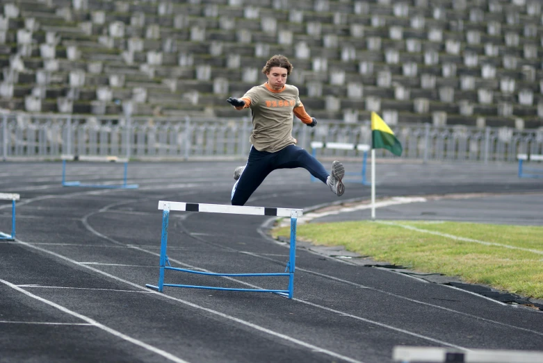 the male athlete jumps to hit the high hurdles in his event