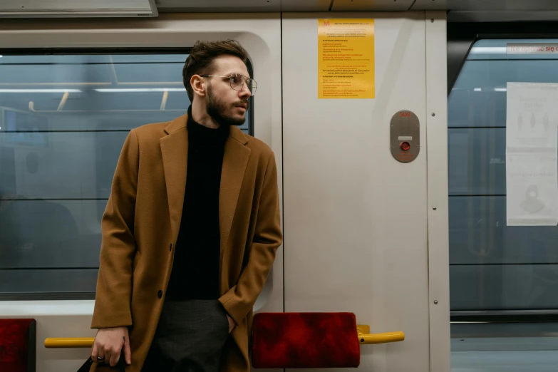 a man in a tan coat leaning against the door