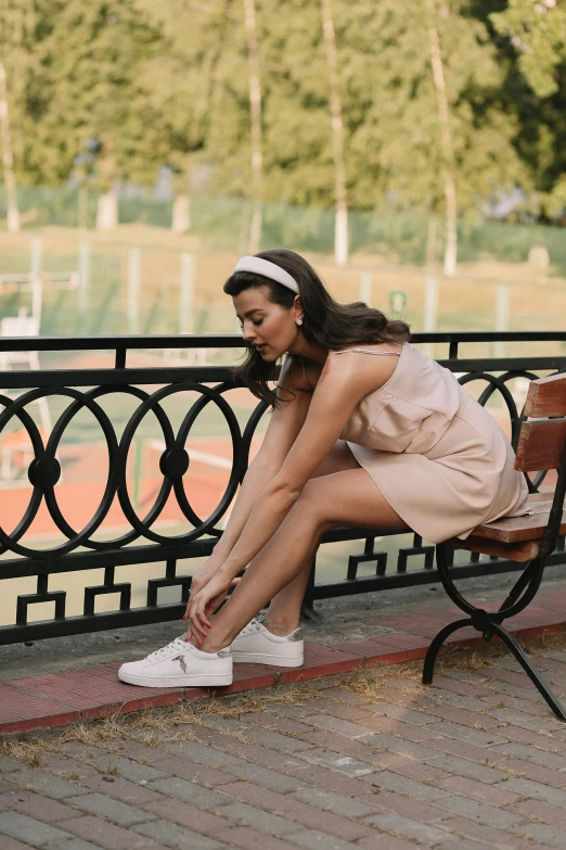 a woman is sitting on a bench looking at the ground