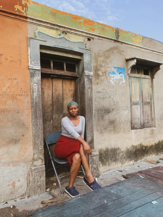 a woman sits on an old building in front of a run down doorway