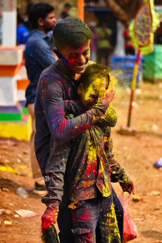 there is a young man standing next to a child covered in yellow and green