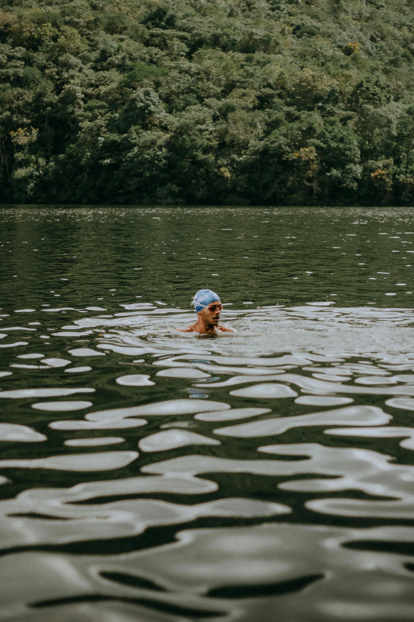 a man swimming in a pond surrounded by green trees