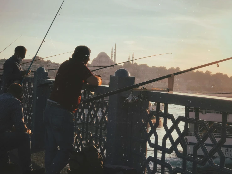 a couple of people standing on a pier fishing