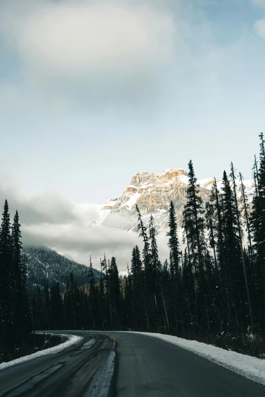 a road with snow and snow covered mountains in the background