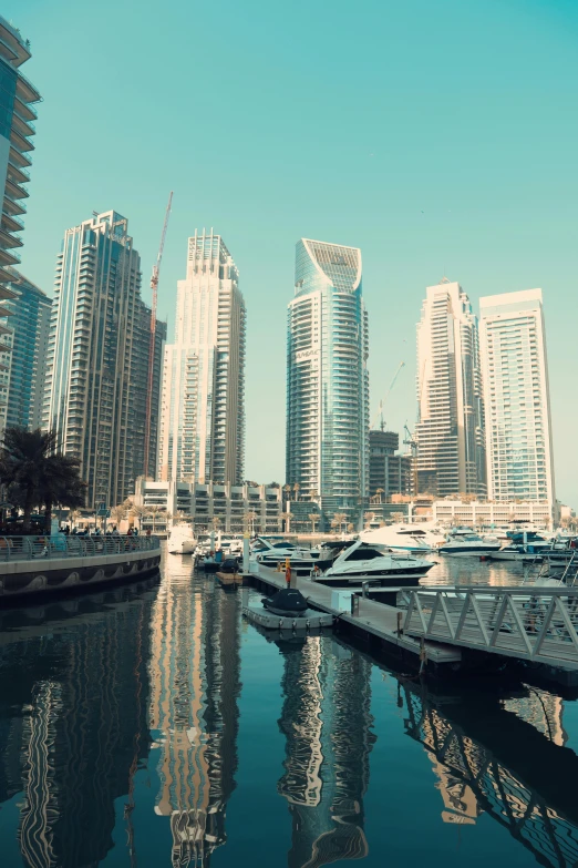 several boats parked along a harbor with large city buildings