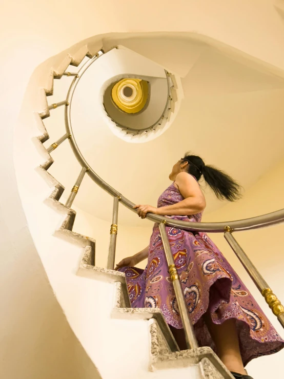 a woman in a pink dress climbs up the stairway