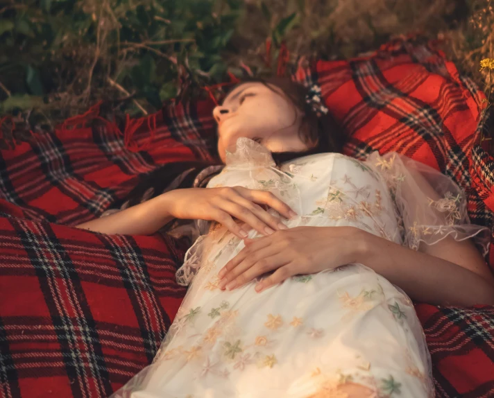 a woman in a floral dress lies on her stomach, covered by a blanket