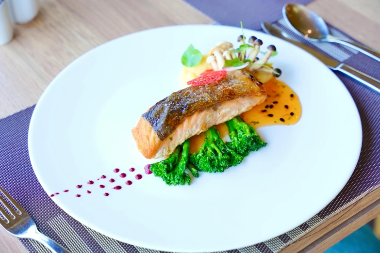 a fish is on the white plate with a bunch of vegetables