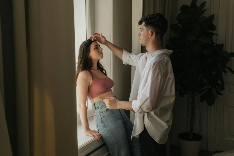 a man putting soing on to his head next to a woman