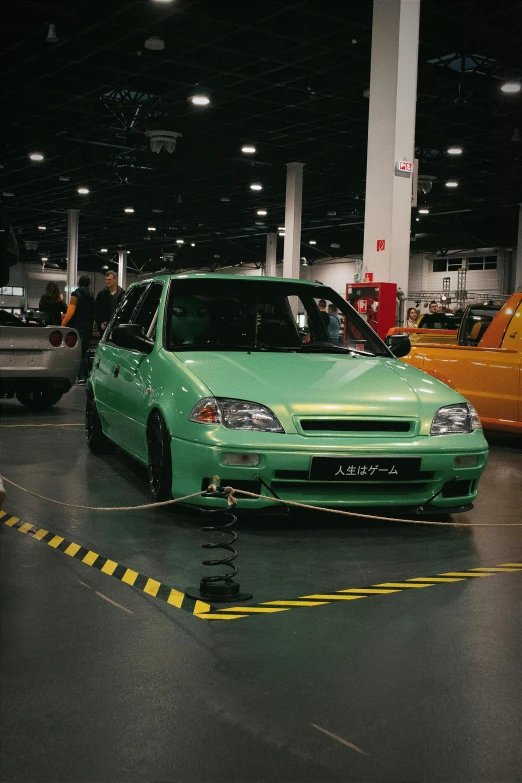 a green car parked on the pavement at a station