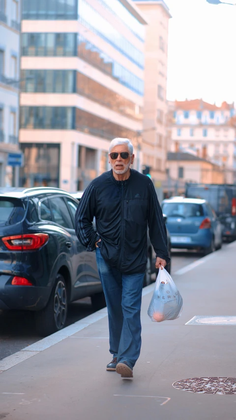 an old man in blue walking on the sidewalk