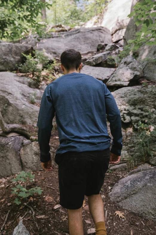 a man walking through a forest with lots of rocks