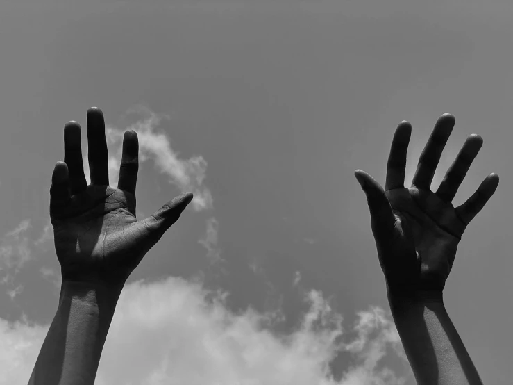 black and white pograph of hands reaching to the sky