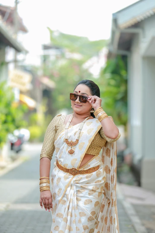 an attractive woman in a white sari walking down the street