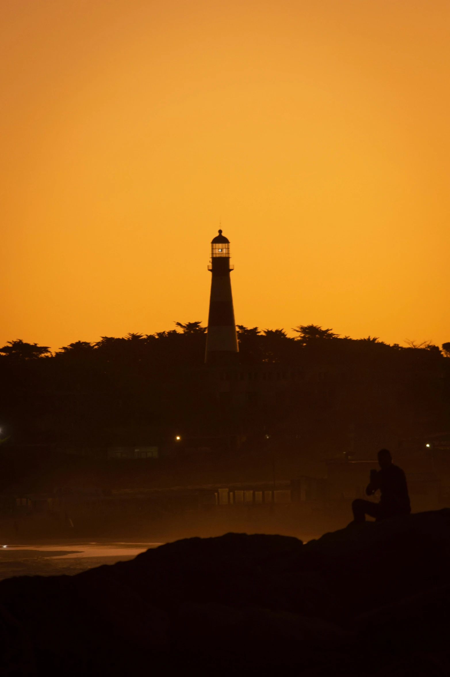 a person sitting on the ground near the lighthouse