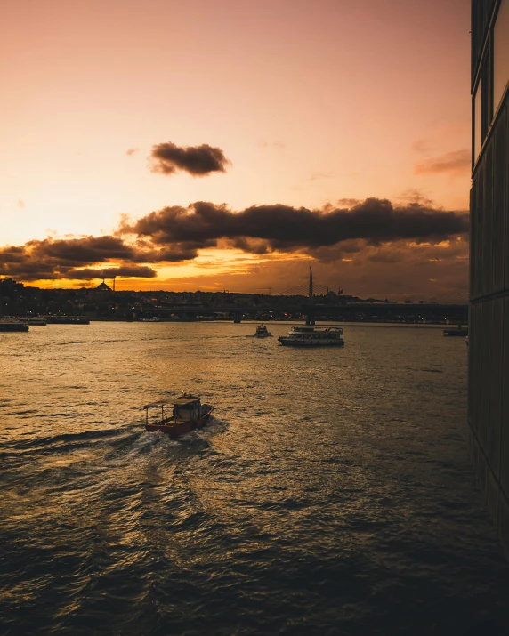 boats in a large body of water at sunset