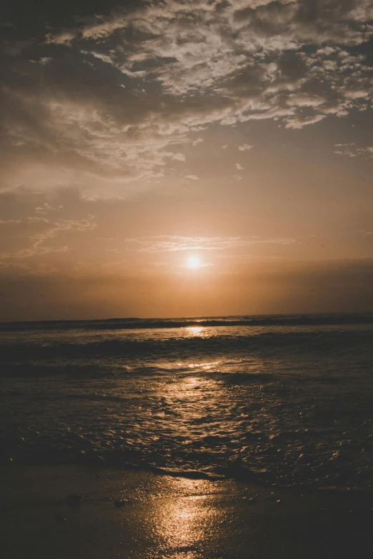 a body of water with clouds and sun in the background