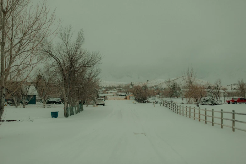 a driveway covered in snow and ice next to a fence