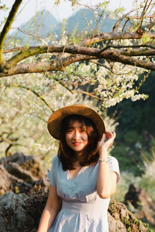 the woman is sitting in the grass near a tree