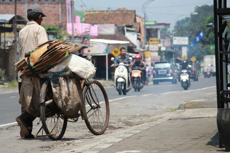 a man on his bicycle carries a load of goods