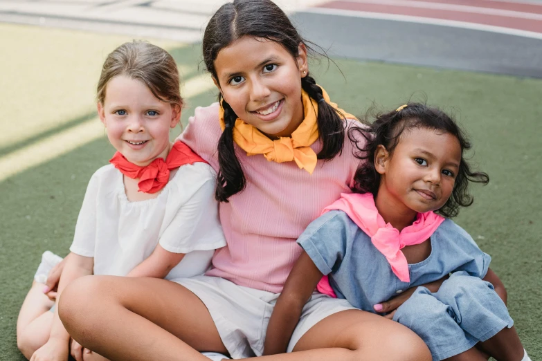 a group of children with one sitting on the ground smiling