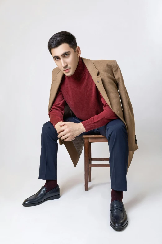 a man is sitting on a stool with a coat over