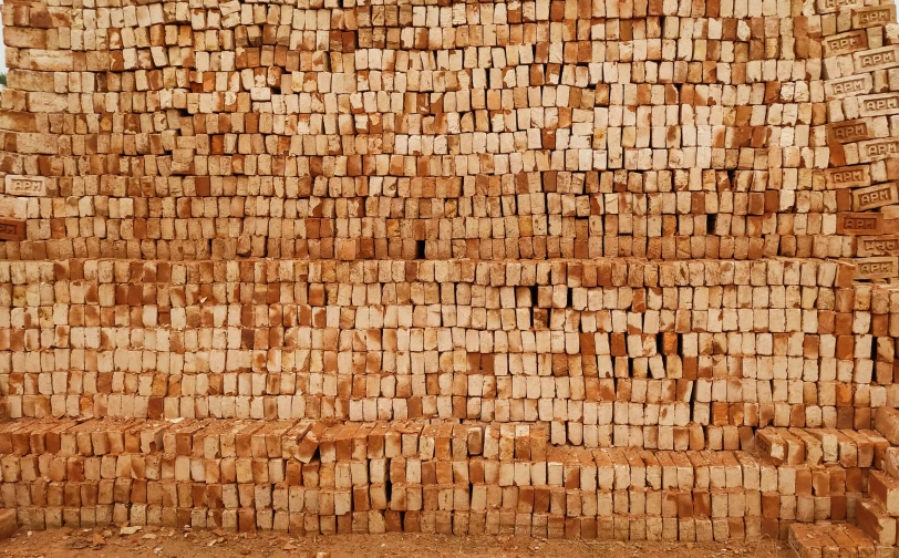 a man is sitting on a bench in front of large blocks of brick