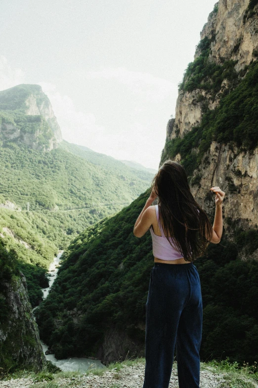 a woman standing on a grassy hill looking out over a valley