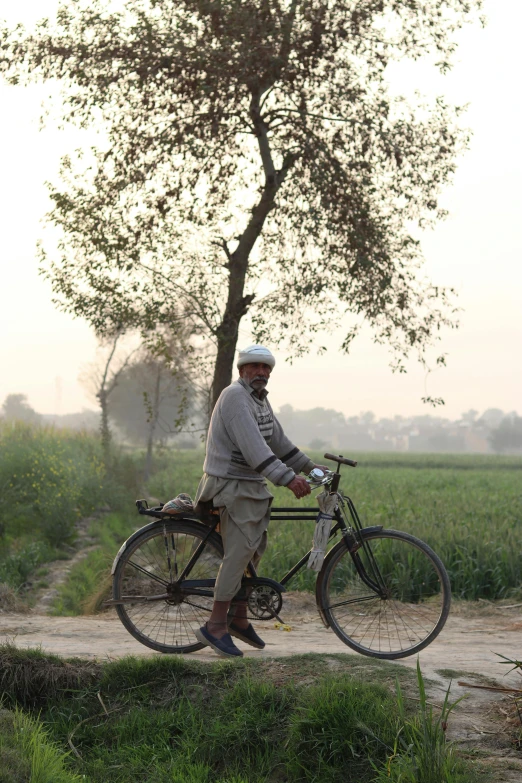 a man is standing with his bicycle on the side of a path