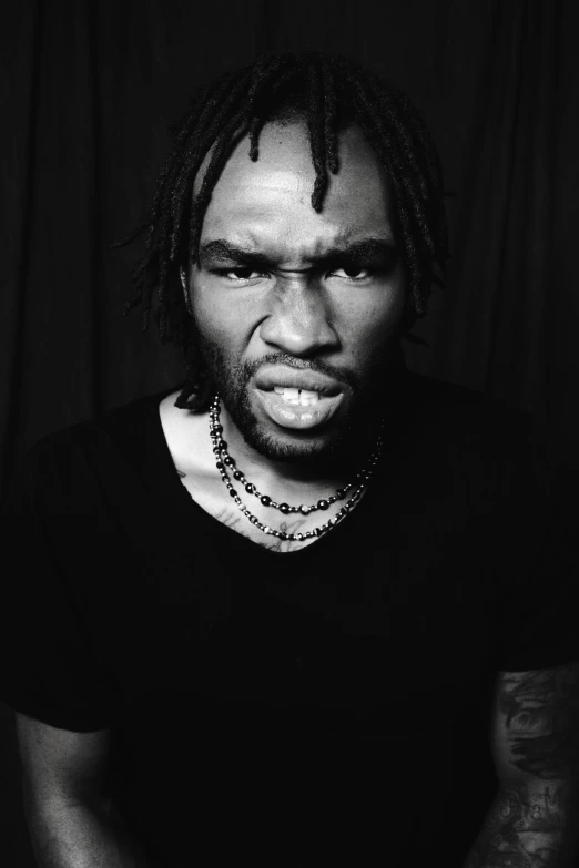 a man is wearing dreadlocks in front of a black background