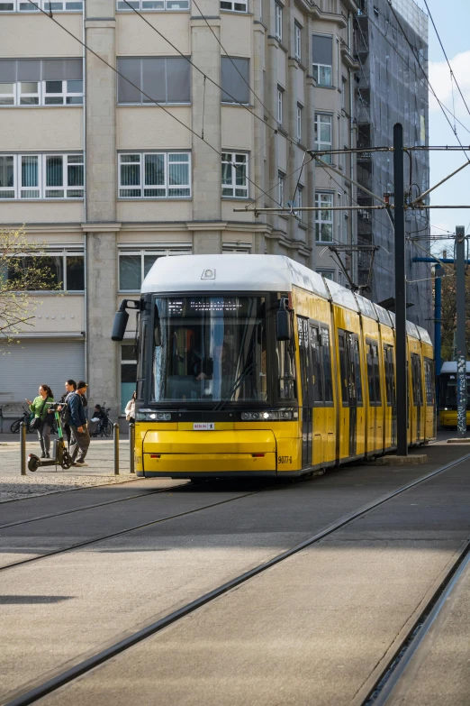 a yellow trolley driving down a street next to tall buildings