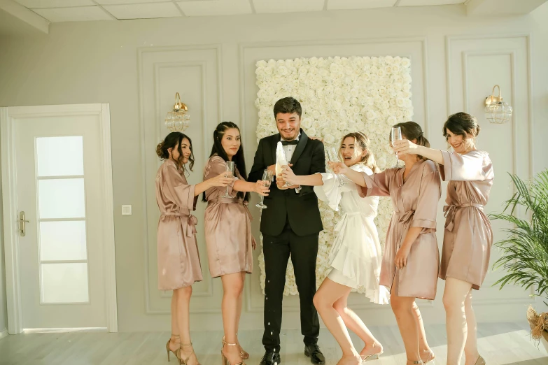 a man holding a glass of wine and a woman with a bouquet posing with friends in a room