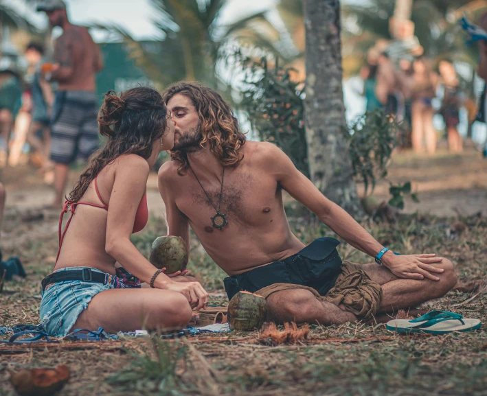 a man and woman sitting on the ground kissing