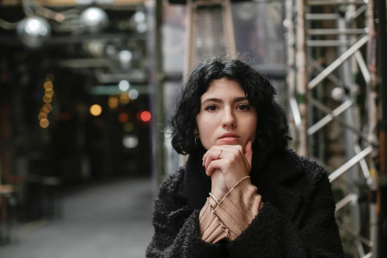 a woman wearing a coat sitting down and looking away from the camera