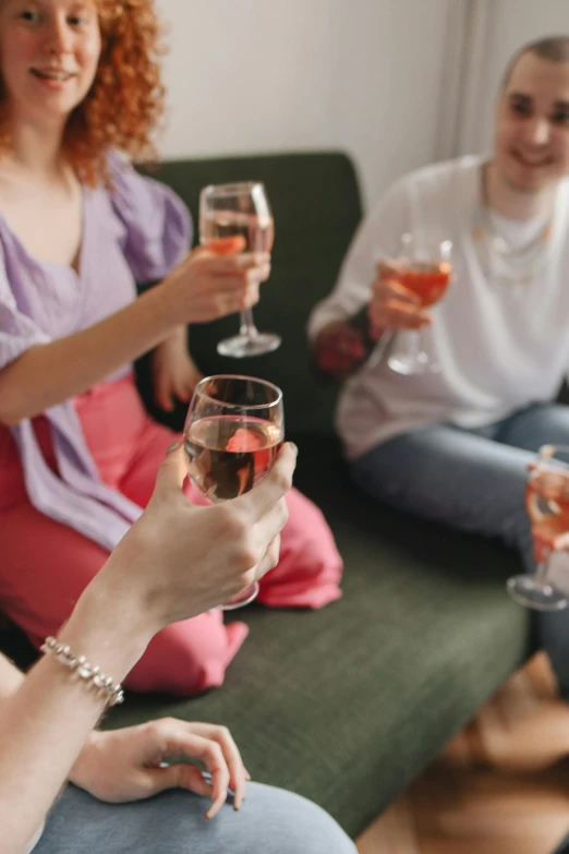 three women toast with a man sitting on a couch behind them