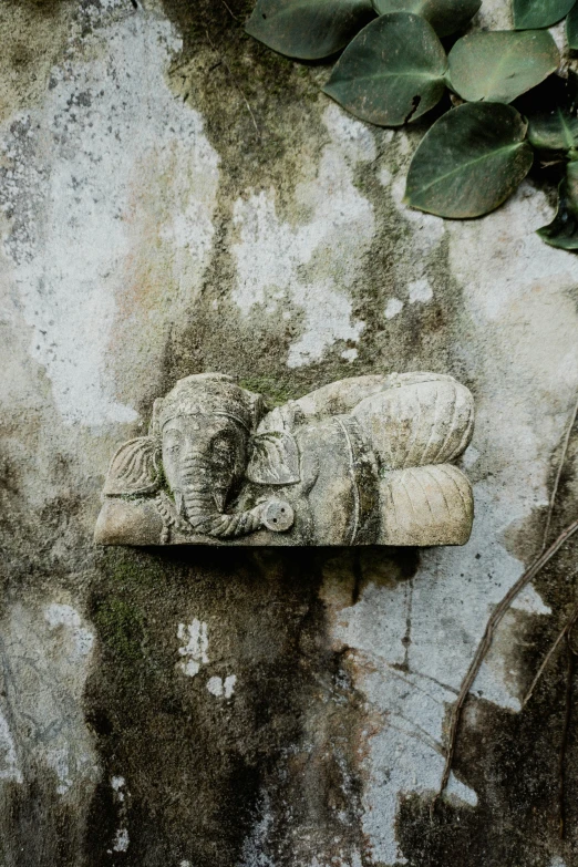 there are two cat figurines lying next to a stone wall