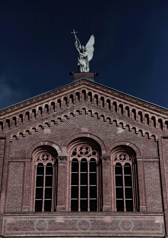 the top of a red brick church with an angel sculpture