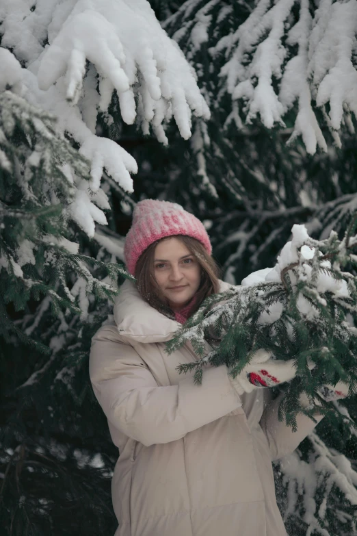 a woman is holding onto a snowy tree